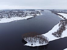 Photographie aérienne hivernale de la rivière Volkhov, avec en arrière-plan le pont de Deverianitsy. Sur les rives, l'on distingue des maisons individuelles et des bâtiments soviétiques.