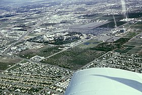 1965 aerial photo of Anaheim Disneyland, Disneyland Hotel with its Monorail Station. The Disneyland Heliport, surrounding orange groves, Santa Ana Freeway (now I-5) and the Melodyland Theater in the round, and part of the City of Anaheim. Anaheim Stadium can be seen under construction near the upper left.