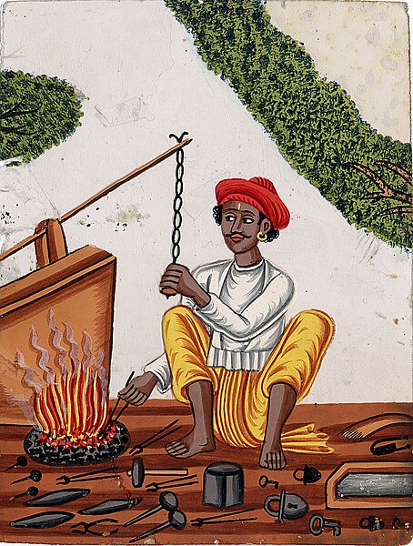 File:A blacksmith in front of his fire with one hand on a chain attached to the bellows.jpg