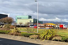 View across the A8 dual carriageway main road, with a temporary funfair on the former East India Harbour docklands site to the right of the arts centre. Beacon Arts Centre from A8.jpg
