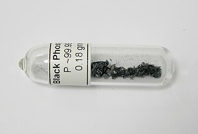 a glass jar turned on its side containing a small amount of tiny black crystalline shards.