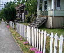 Classic white picket fence next to a sidewalk showing some signs of aging Classic Picket Fence.JPG