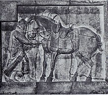 kamenná deska s reliéfem muže-vojáka (vlevo) držícího za uzdu osedlaného koně (v centru a vpravo)