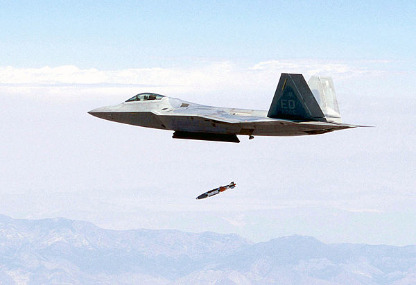 A F-22 releases a JDAM from its center internal bay while flying at supersonic speed