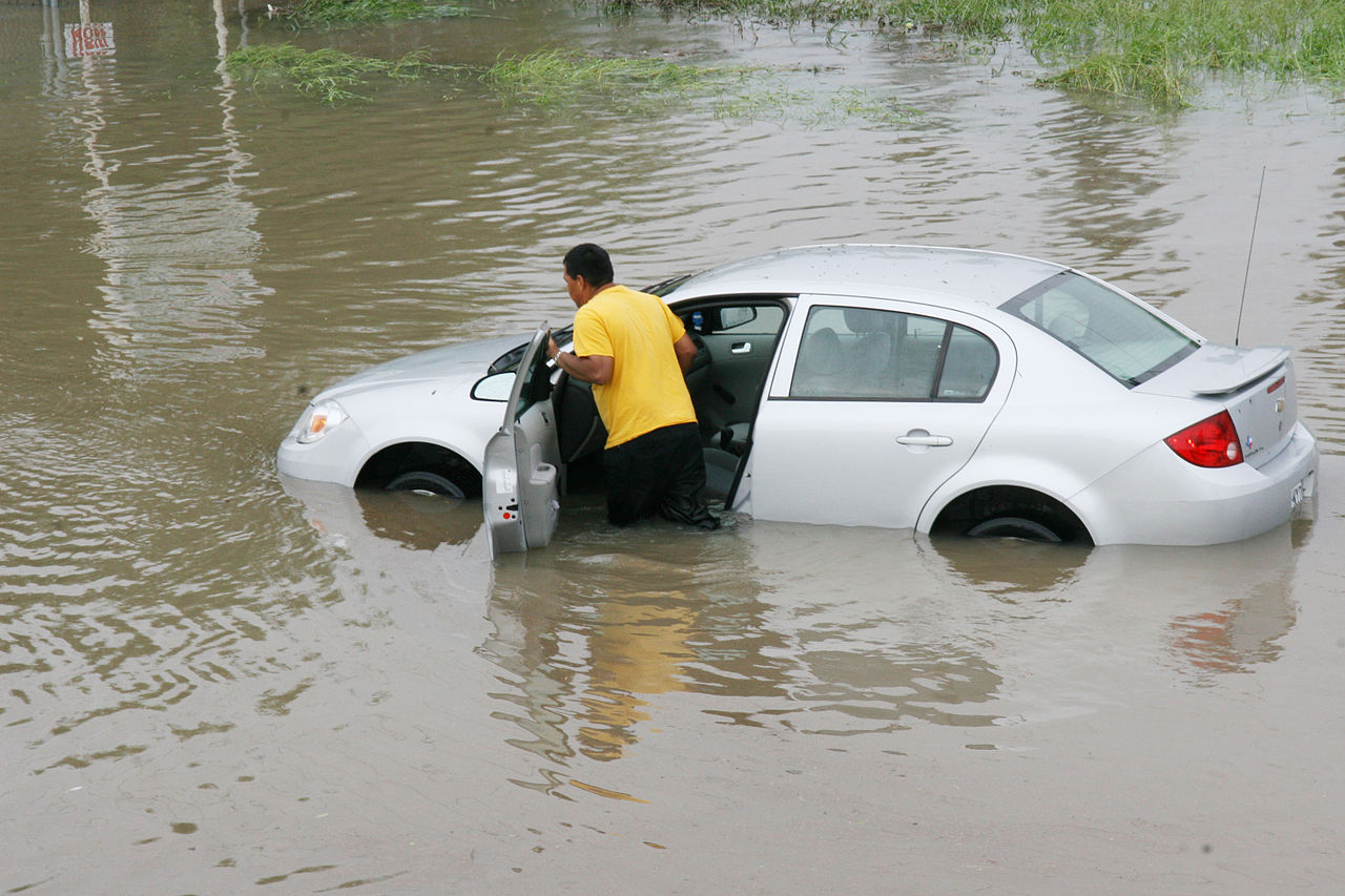 Resident pushing a car through flood waters