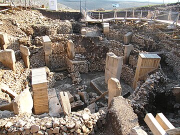 Vista interior de un recinto con muros circulares de piedra y piedras levantadas.  Algunos están empaquetados en tablas de madera.