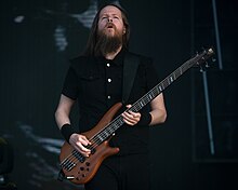 Image d'un homme avec une barbe brune jouant de la basse élèctrique