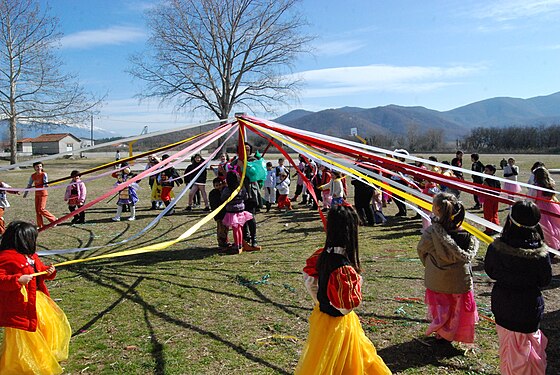 School children dressed up for carnival going round a maypole.