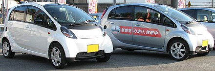 Two Mitsubishi i kei cars photographed together in Japan. The silver i is a dealer model for customers to test drive.