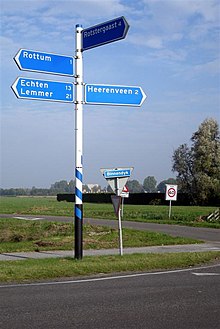 Signposts showing number of kilometres to nearest towns. A roadsign showing the speed limit in kilometres an hour is visible in the middle distance. N924 wegwijzer 06.JPG