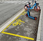 Bicycles and kick scooter parked a marked placed on the floor