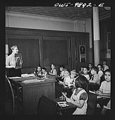 Public school teacher showing the first grade pupils pictures of Indians