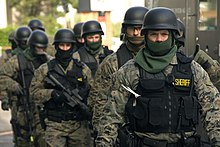 Special Weapons and Tactics (SWAT) team members, some armed with assault rifles, preparing for an exercise SWAT team prepared (4132135578).jpg