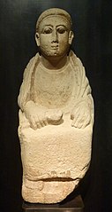 seated figure in a long tunic, a piece of cloth in hand