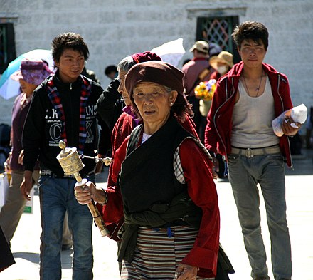 Tibetan woman with prayer wheel in Lhasa street