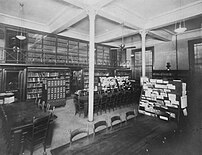 Black-and-white photo of an empty room with tables and bookshelves