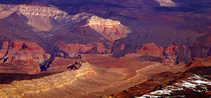 Вид, показывающий затвердевшие потоки темной вулканической породы, спускающиеся по краю каньона