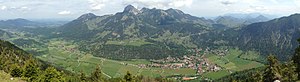 Blick auf Bayrischzell (rechts) mit dem Hausberg Wendelstein, davor der Weiler Hochkreut, links der Gemeindeteil Osterhofen, ganz links das Dorf Geitau, ganz rechts das Sudelfeld, hinten rechts der Chiemsee und die Chiemgauer Alpen