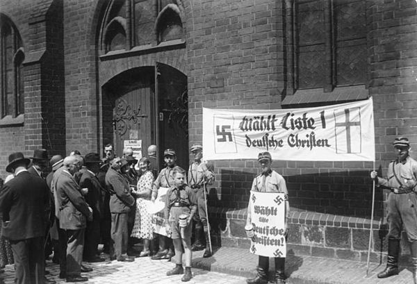 Stormtroopers holding Deutsche Christen propaganda during the Church Council elections on 23 July 1933 at St. Mary's Church, Berlin