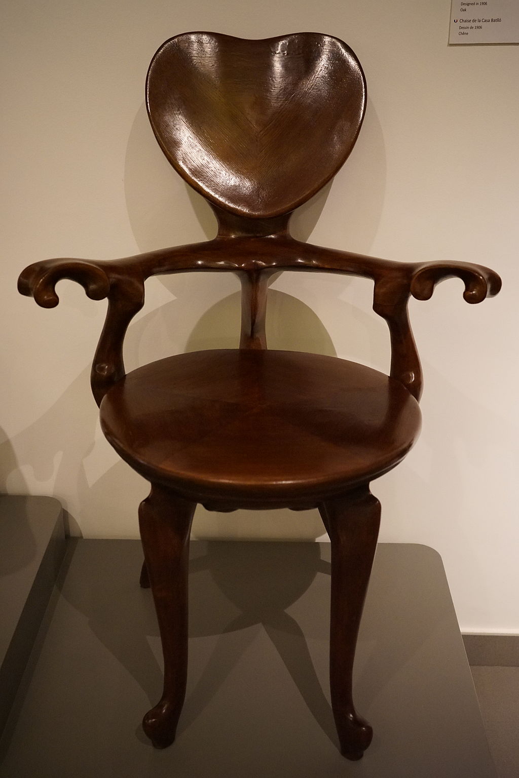 Chair in oak, designed 1906: Dark wood chair with a heart-shaped back and curvy arms. 