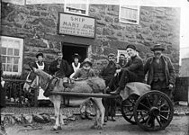 A donkey-cart and several people in front of an inn