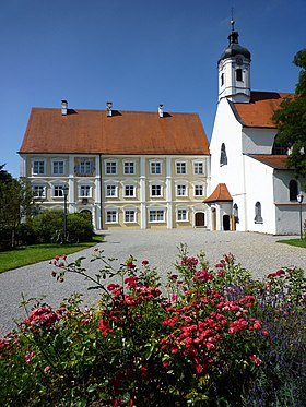 Színes fénykép, amely jobb oldali templomot, bal oldalon háromemeletes épületet mutat