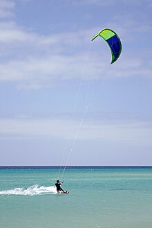A kiteboarder is pulled across the water by a power kite Kitesurfing Sotavento.jpg