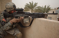 A U.S. 2nd Infantry Division soldier pulls security on top of a roof using an M240B with an attached M145 and AN/PEQ-2.