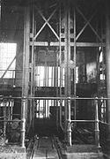 Fotografía en blanco y negro que muestra un hueco de ascensor, la base del cabezal y el orificio del hueco.