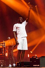 Stormzy scored six top 10 entries this year. "Vossi Bop" debuted at number-one in May and became his first single to top the UK chart. He also reached the top spot thanks to his appearance on Ed Sheeran's "Take Me Back to London". "Own It", which also featured Sheeran as well as Nigerian singer Burna Boy, would reach its peak of number-one on 9 January 2020. Roskilde Festival Stormzy-2.jpg