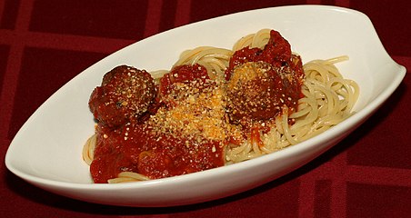 Restaurant presentation of spaghetti and meatballs with Parmesan cheese.