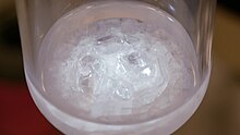 clear crystals under a clear liquid at the bottom of a glass flask