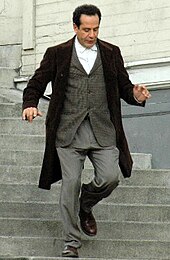 Photo d’un homme dévalant des escaliers avec un costume et un manteau.