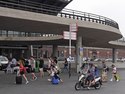 Travelling people are walking into the entrance of Amsterdam Central Station, under the concrete construction of the bus station; free photo Amsterdam of people and modern architecture by Fons Heijnsbroek, August 2020 - The Netherlands