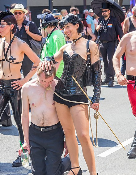 A dominatrix wearing a corset with a submissive man at 2013 Cologne Pride.