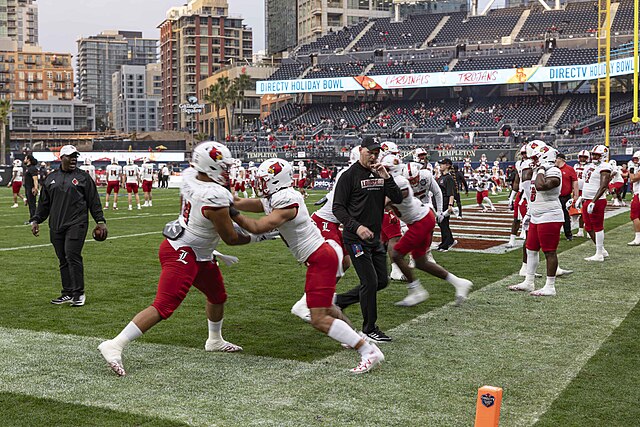 The Louisville Cardinals football team on the field at Petco Park before the 2023 Holiday Bowl