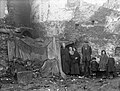 A family pose beside a make-shift shelter Alexander Street, Waterford, Ireland, 1920s (6805869735).jpg