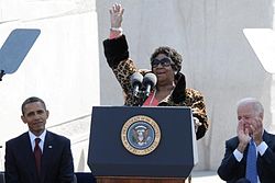 Aretha Franklin speaks to the crowd at the dedication of the Dr. Martin Luther King Jr. Memorial. Seated at left is President Barack Obama, and at right Vice President Joe Biden.