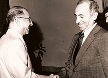 Schwarz-Weiß-Foto von zwei Männern in Anzügen, die sich die Hände schütteln