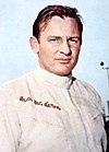 Bruce McLaren in racing overalls looking slightly to the right of the camera