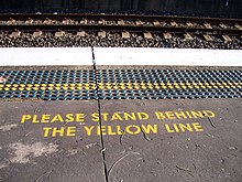 A typical message asking passengers to stand behind the yellow line, and tactile paving near the edge of the platform CityRail yellow line.jpg