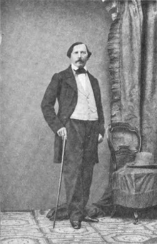 Footage of Félix Milliet, posing in costume with a cane in his hand.