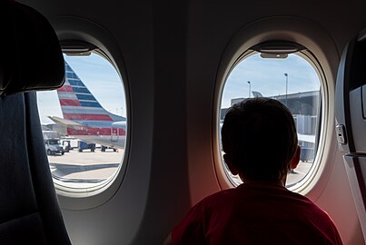 Gabriel peeking out of an airplane window, O'Hare Airport, Chicago, Illinois, US