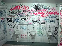 Graffiti on wall behind urinals