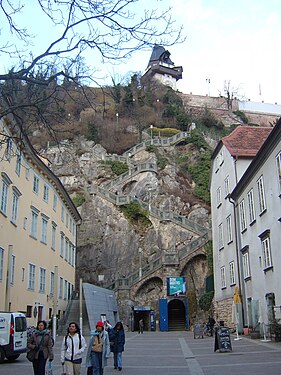 Schloßbergplatz, Blick von der Sackstraße ostwärts. Reinerhof (re.) und „Alte Münze“ (li.). Mittig der „Kriegssteig“, daneben die überwucherten Reste der Stadtmauer.