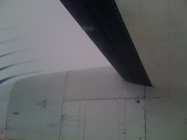 The black rubber deicing boot on the wing of a Bombardier Dash 8 Q400 passenger aircraft is inflated with air, producing ridges to crack and dislodge 