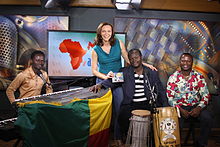 Maxwell interviewing a musical group from Benin on Voice of America Maxwell at VOA.jpg