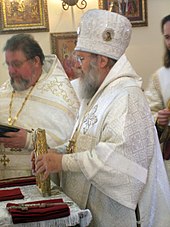 Orthodox bishop wearing a sakkos Placing Gospel Book onto Antimension at end of Liturgy.jpeg