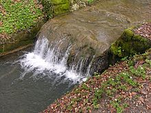 Sediment builds up on human-made breakwaters because they reduce the speed of water flow, so the stream cannot carry as much sediment load. StoneFormationInWater.jpg
