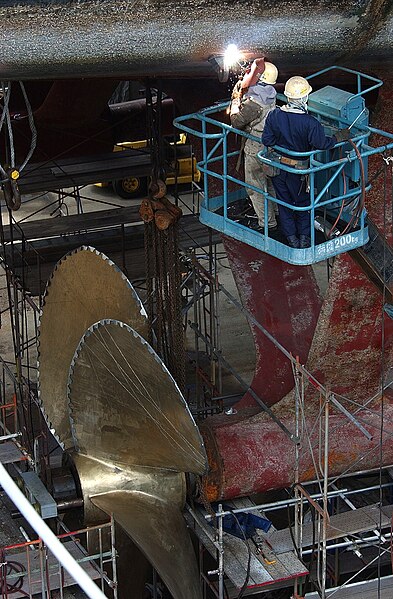 File:US Navy 030703-N-8218W-029 Japanese National workers weld a pad eye to the hull of USS Kitty Hawk (CV 63) in preparation to remove one of the ship's screws.jpg